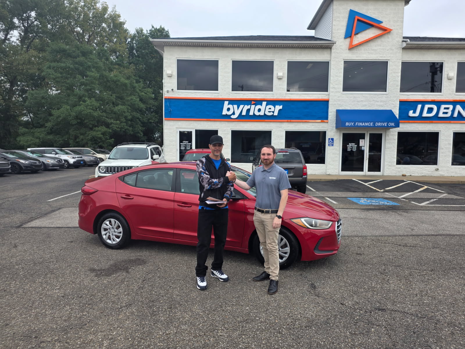 Byrider Akron customer shaking hands with a sales consultant in the dealership lot after his used Hyundai Elantra was financed in-house