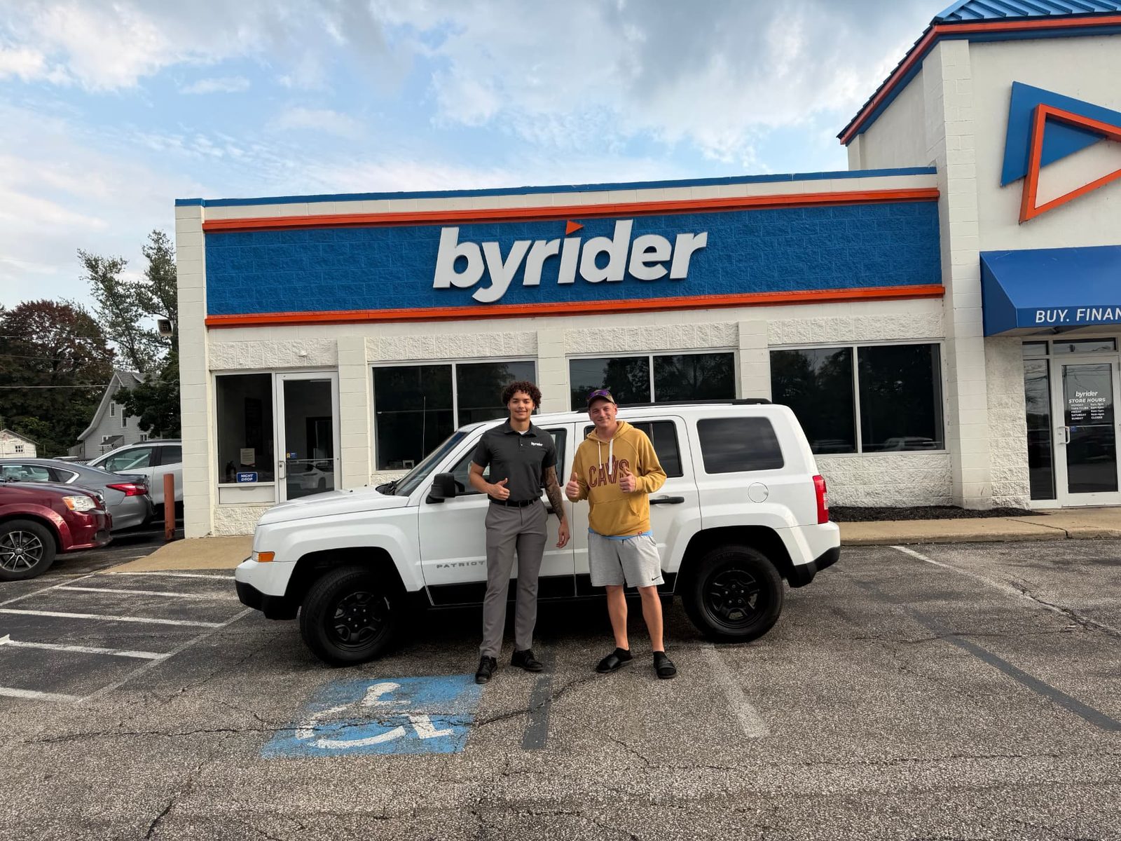 Byrider Ashtabula customer and salesperson beside their used Jeep Patriot at the Ashtabula, Ohio dealership