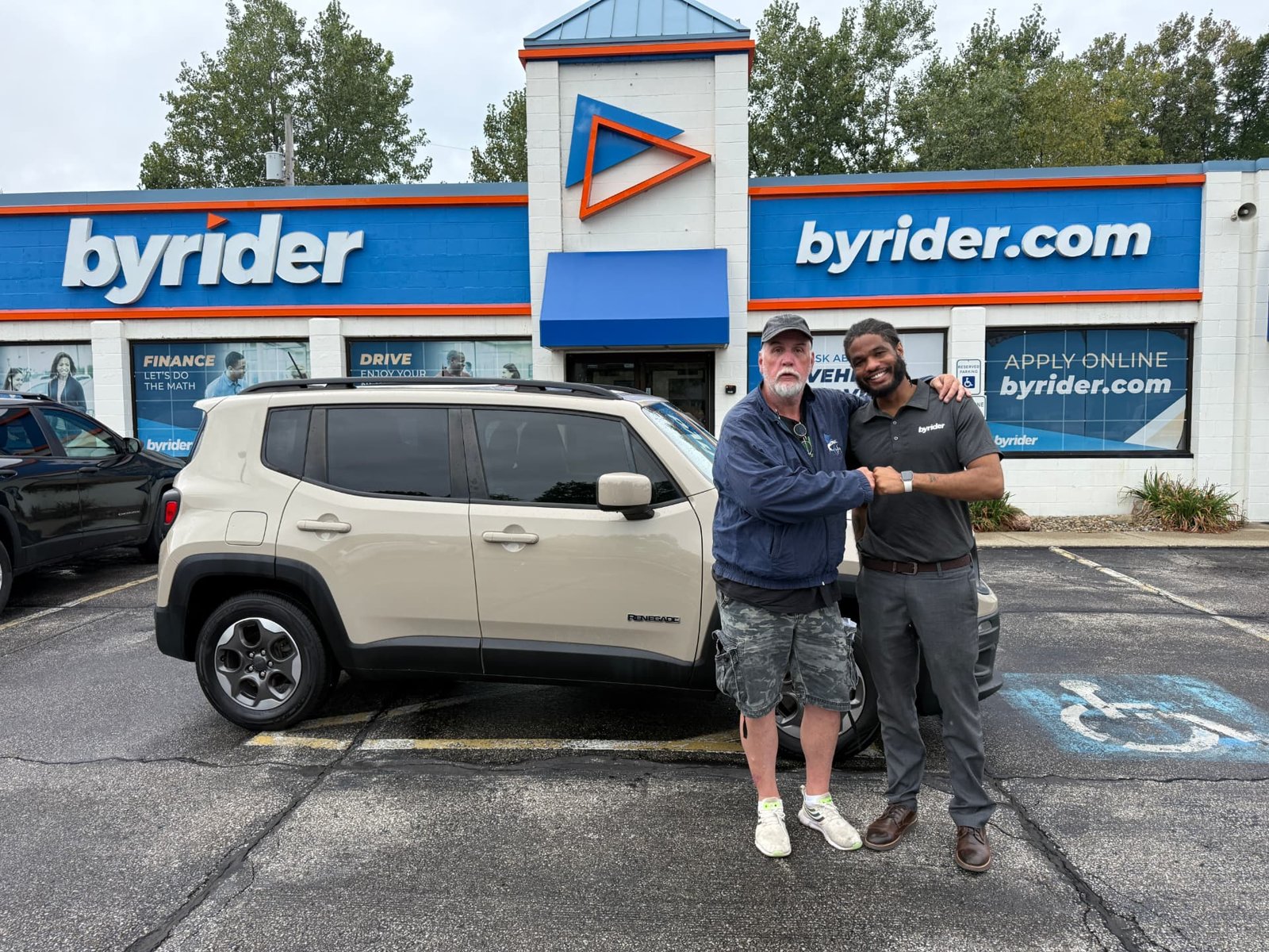 Byrider Amherst customer and salesperson beside their used Jeep Renegade at the Amherst, Ohio dealership