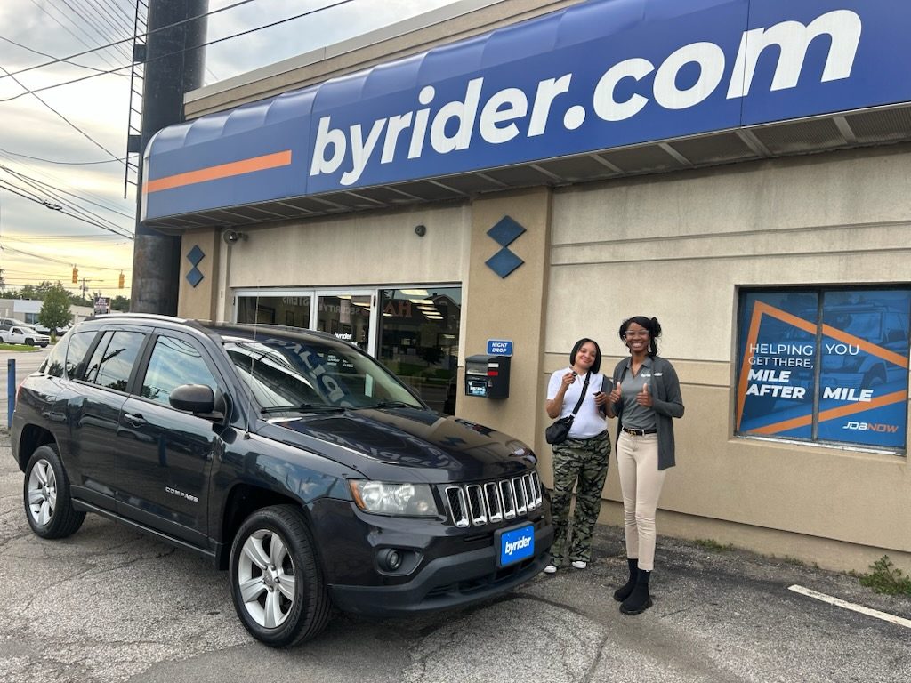 Byrider Cleveland customer and salesperson beside their used Jeep Compass at the Cleveland, Ohio dealership