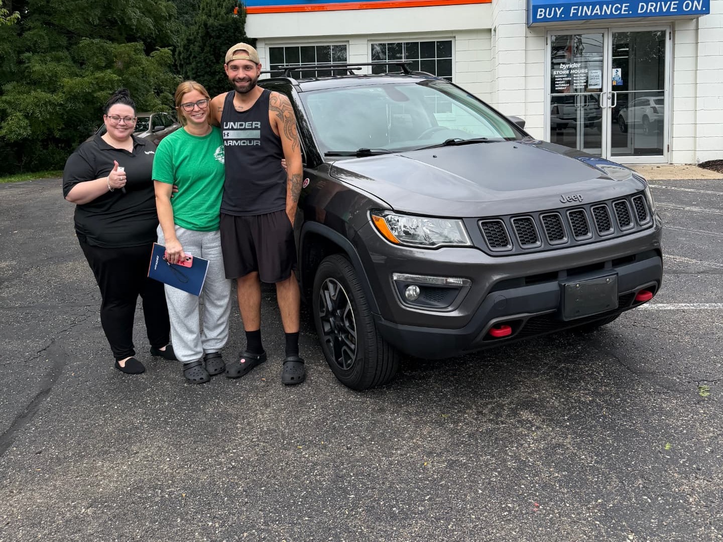 Byrider Wooster customers and salesperson beside their used Jeep Compass at the Wooster, Ohio dealership