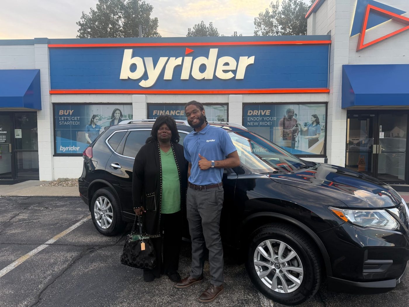 Byrider Amherst customer and salesperson beside their used Nissan SUV at the Amherst, Ohio dealership