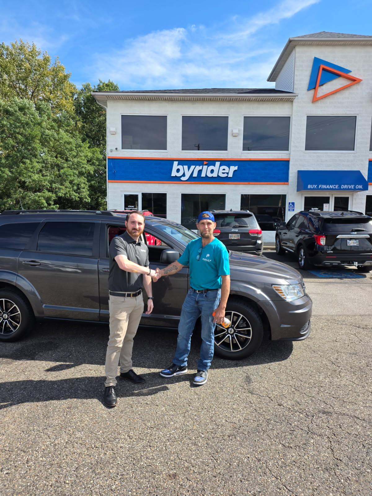 A happy Byrider customer shaking hands after buying a used Dodge Journey in Akron, Ohio