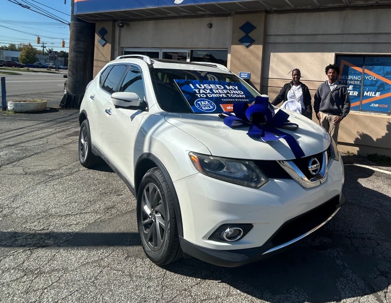 Byrider customers standing beside their Nissan Rogue decorated with a delivery bow and an I Used My Tax Refund to Drive Today sign during the Tax Refund Sale in Ohio